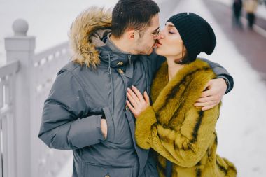 Güneşli bir kış gününde parkta yürüyen mutlu çift.