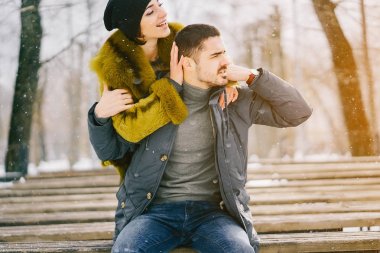 Güneşli bir kış gününde parkta yürüyen mutlu çift.