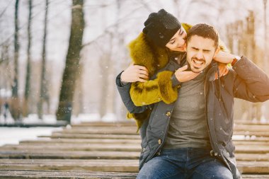 Güneşli bir kış gününde parkta yürüyen mutlu çift.