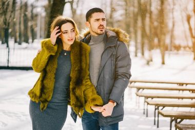 Güneşli bir kış gününde parkta yürüyen mutlu çift.