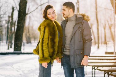 Güneşli bir kış gününde parkta yürüyen mutlu çift.