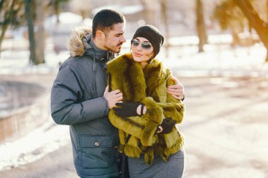 Güneşli bir kış gününde parkta yürüyen mutlu çift.