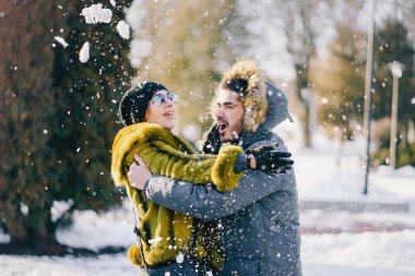 Güneşli bir kış gününde parkta yürüyen mutlu çift.