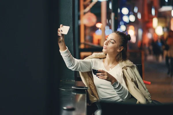 Lány ül a kávézó előtt használja a telefonját — Stock Fotó