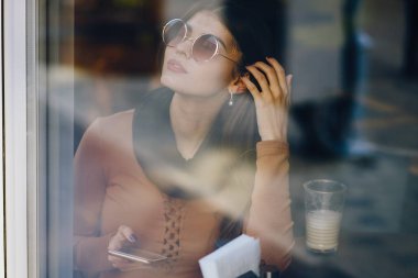 Esmer kız restoranda telefon kullanıyor.