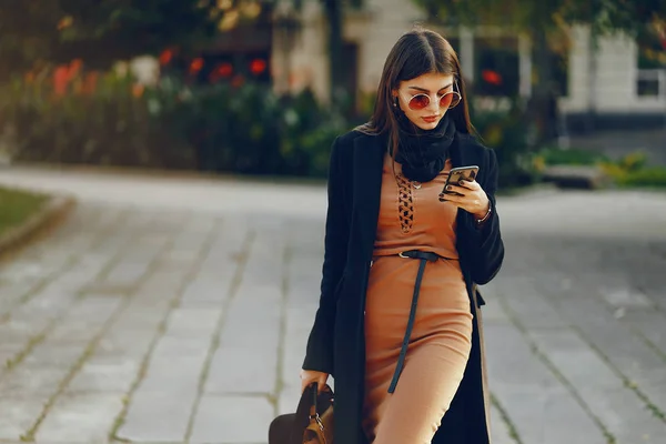 Snygg flicka promenader genom staden när du använder sin telefon — Stockfoto