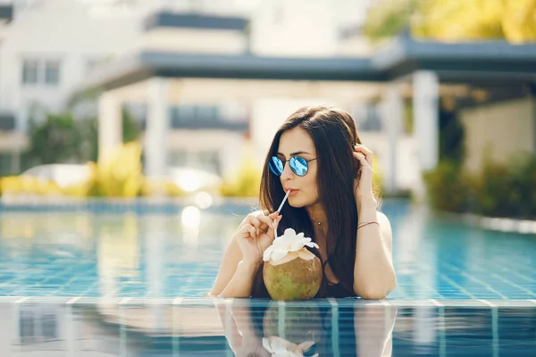 Menina morena comendo frutas na piscina — Fotografia de Stock