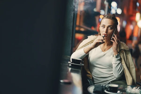 Dívka sedí před kavárnou pomocí telefonu — Stock fotografie