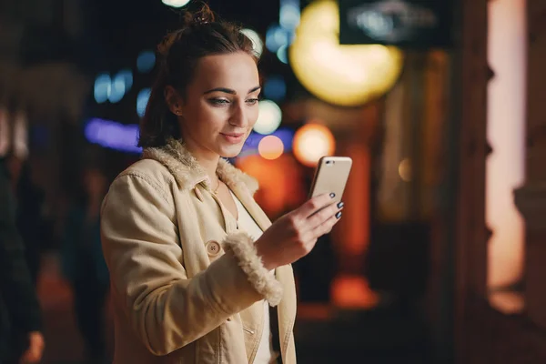 Lány ellenőrzi a telefonját odakint éjszaka — Stock Fotó