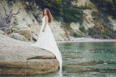 Su kenarında yürüyen muhteşem beyaz elbiseli güzel uzun saçlı gelin
