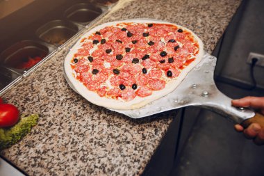 Mutfakta şef pizza hazırlıyor.