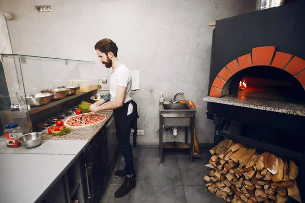 Chef in the kitchen prepares pizza