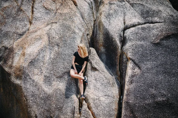 Blond dívka sedí na skalní útvar — Stock fotografie