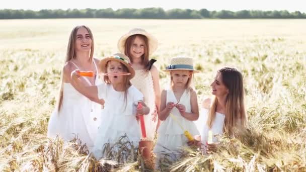 Матери с дочерьми в шляпах позируют на пшеничном поле — стоковое видео
