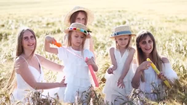 Девушки в белых платьях с пузырьками проводят время на пшеничном поле — стоковое видео