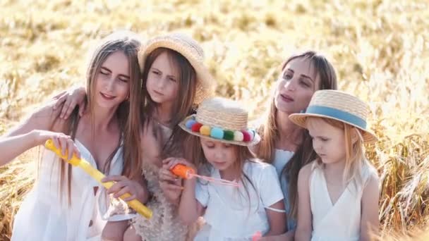 Meninas em vestidos brancos com bolhas passar tempo no campo de trigo — Vídeo de Stock