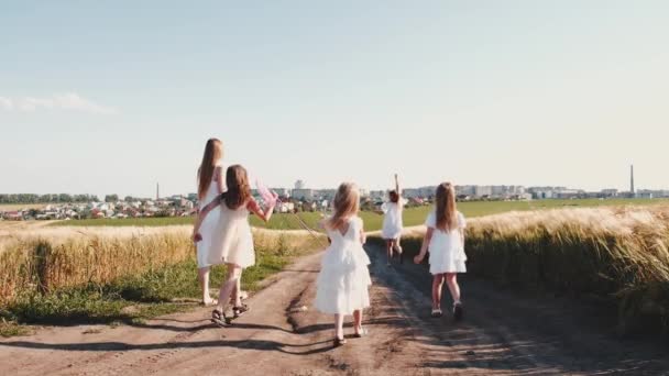 Chicas en vestidos blancos en el camino que corre con la red de mariposas y cometa — Vídeos de Stock