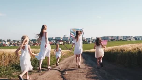 Девушки в белых платьях на дорожке бегают с сеткой от бабочек и воздушным змеем — стоковое видео