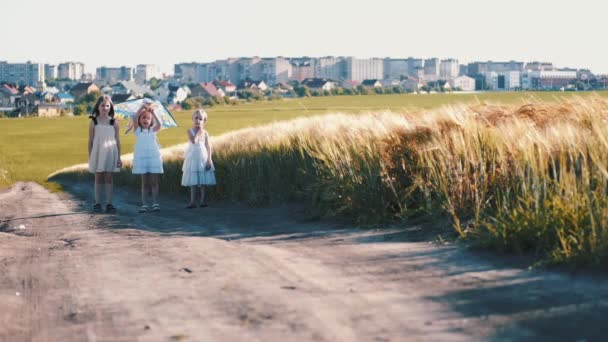 Tre bambine in abiti in piedi sul sentiero con aquilone — Video Stock