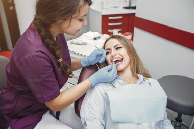 Güzel kız dişçi ofisinde oturuyor.
