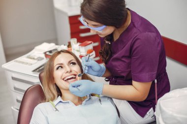 Güzel kız dişçi ofisinde oturuyor.