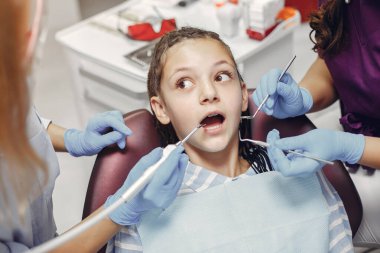 Güzel küçük kız dişçi ofisinde oturuyor.