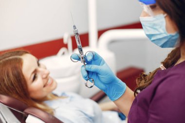 Güzel kız dişçi ofisinde oturuyor.