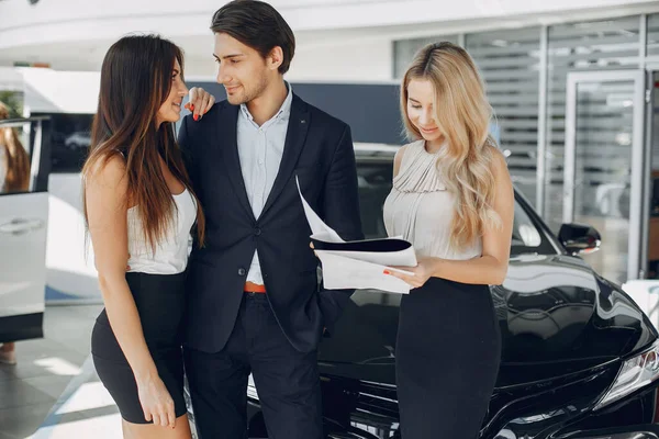 Stylish and elegant people in a car salon — Stock Photo, Image