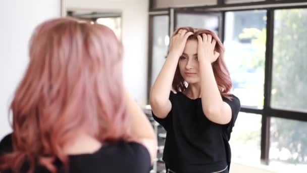 Chica mirando la nueva imagen en el espejo en el salón de belleza — Vídeo de stock
