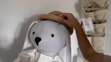 Beyaz odada hasır şapkalı büyük el yapımı tavşan.