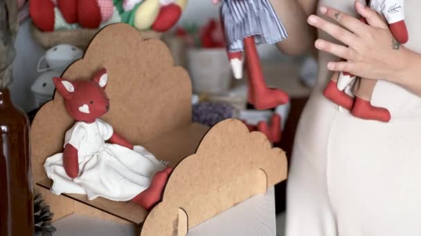 Chica embalaje juguetes hechos a mano en caja en habitación blanca — Vídeo de stock