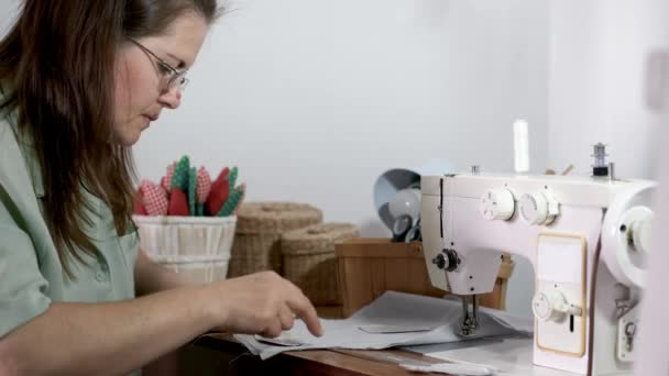 Vrouw met bruin haar naaispeelgoed in kledingfabriek — Stockvideo