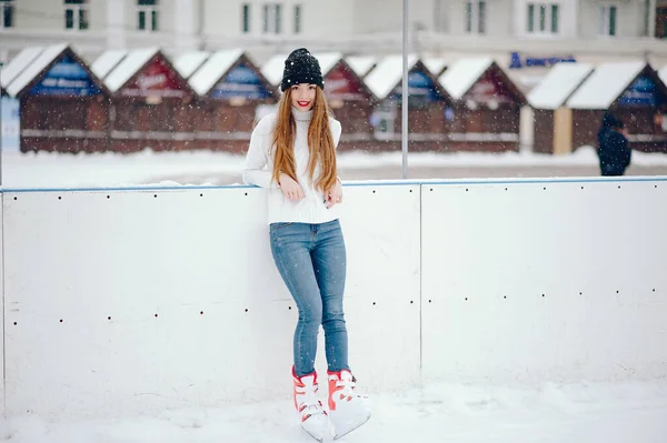 Schattig en mooi meisje in een witte trui in een winterstad — Stockfoto