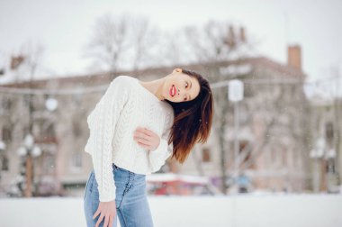 Kış parkında duran beyaz kazaklı genç kız.