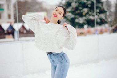 Kış parkında duran beyaz kazaklı genç kız.