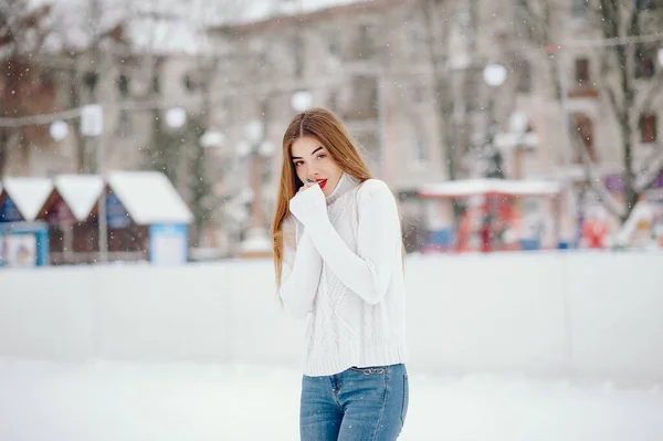 Ung flicka i en vit tröja stående i en vinterpark — Stockfoto