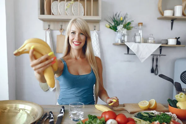 Krásná a sportovní dívka v kuchyni se zeleninou — Stock fotografie