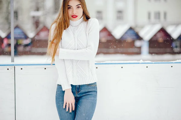 Young girl in a white sweater standing in a winter park — Stock Photo, Image