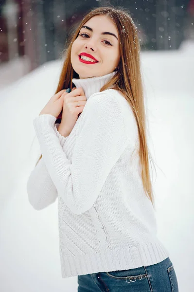 Chica joven en un suéter blanco de pie en un parque de invierno — Foto de Stock