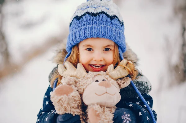 Bambina con un cappello blu che gioca in una foresta invernale — Foto Stock