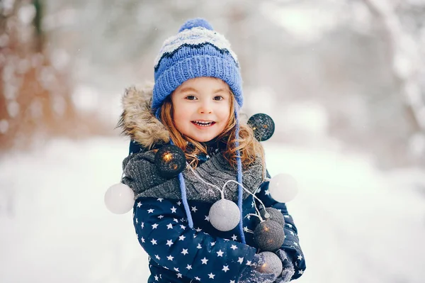 Bambina con un cappello blu che gioca in una foresta invernale — Foto Stock