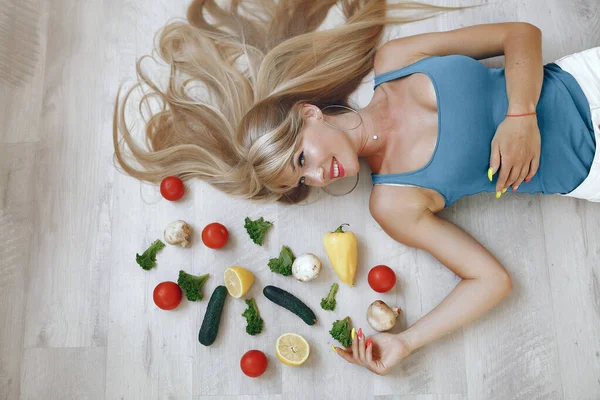 Menina bonita e desportiva em uma cozinha com um legumes — Fotografia de Stock