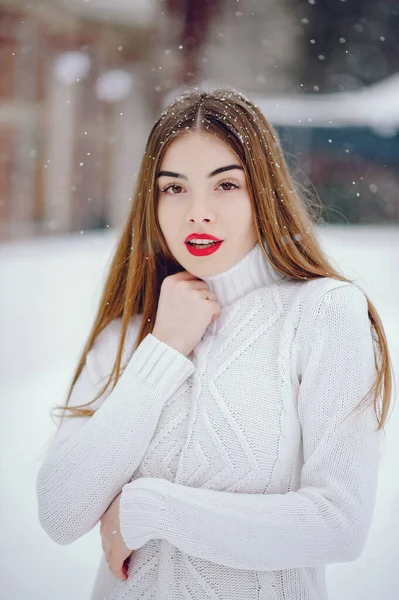 Młoda dziewczyna w białym swetrze stojąca w zimowym parku — Zdjęcie stockowe