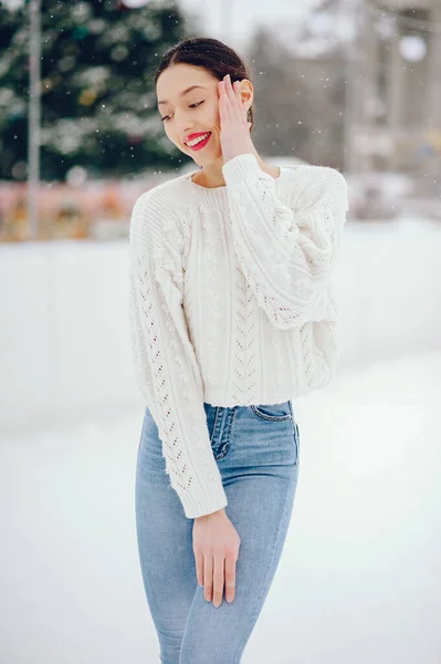 Молодая девушка в белом свитере стоит в зимнем парке — стоковое фото