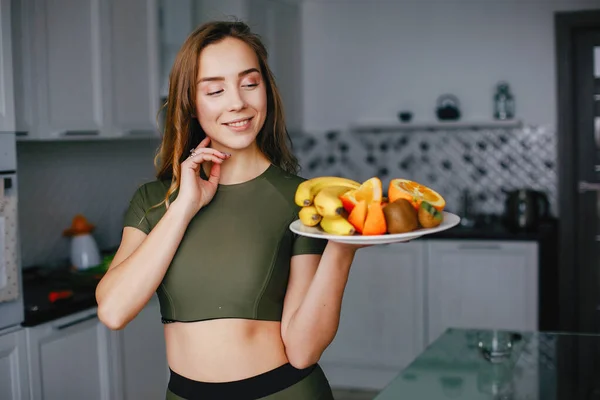 Menina de esportes em uma cozinha com legumes — Fotografia de Stock