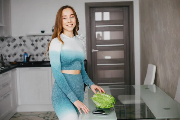 Sportmädchen in einer Küche mit Gemüse — Stockfoto