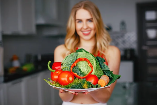 Sport meisje in een keuken met groenten — Stockfoto