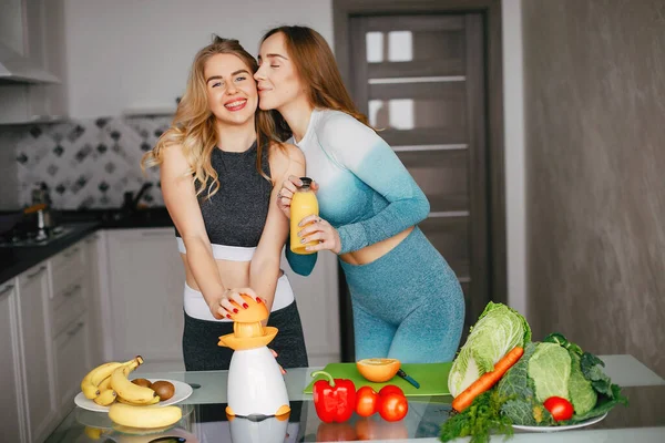 Zwei Sportlerinnen in einer Küche mit Gemüse — Stockfoto