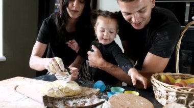 Küçük kızı olan bir çift modern mutfakta kek hazırlıyor.