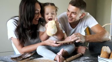 Aile üyeleri modern mutfakta hamur yoğuruyorlar.